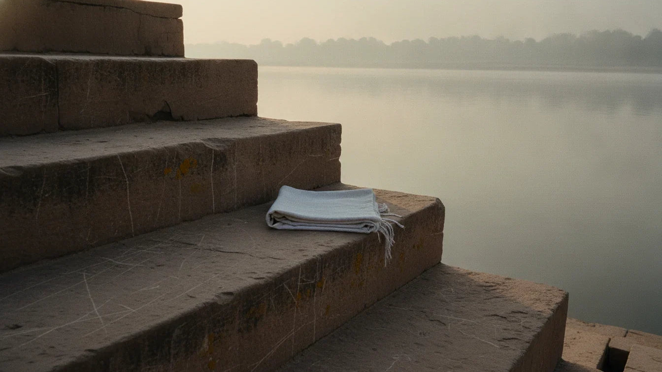 Snana in the Bhavaprakasha: empty stone bathing steps leading into a misty river at dawn, a folded white cloth on a step
